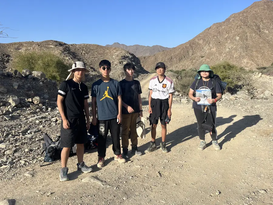 An expedition group stands together on the trail before setting off